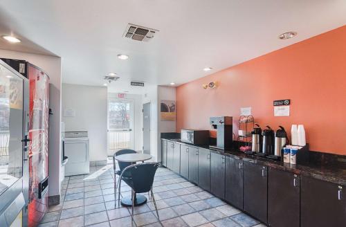 eine Küche mit orangefarbenen Wänden und einer Theke mit Stühlen in der Unterkunft Motel 6-Terrell, TX in Terrell
