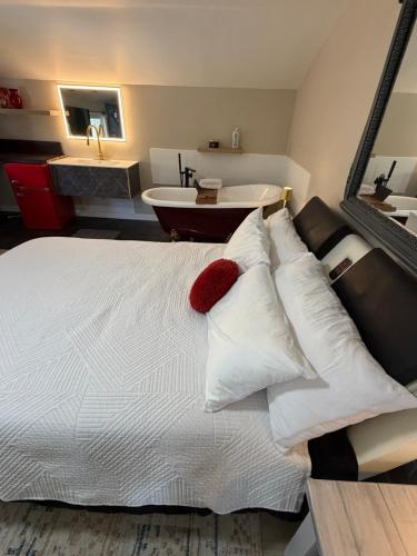 a bedroom with a bed with white pillows and a tub at Sip and Soak, hotel-style room in Calgary