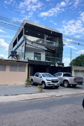 two cars parked in a parking lot in front of a building at Suíte caripi in Barcarena
