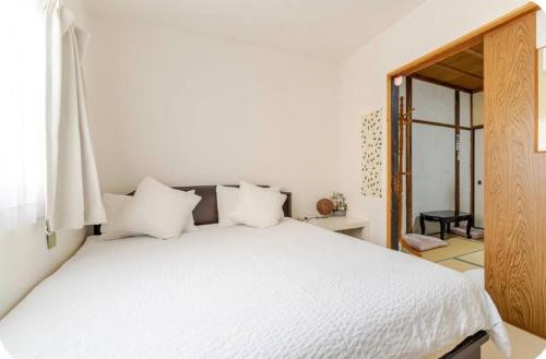 a bedroom with a white bed with white pillows at 2 floors japanese style, direct to KIX, 10mins train to Namba, 5mins walk to stn , 2-6ppl in Osaka