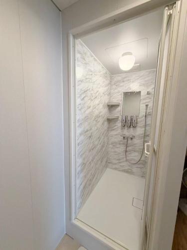 a bathroom with a shower with a glass door at ゲストハウス 華園 in Furano