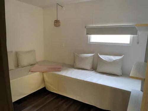 a small room with a bed with pillows and a window at Cozy Coco Sweet Glamping Tent for 4 in Rijkevorsel