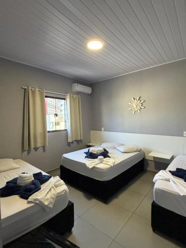 ein Zimmer mit zwei Betten und einem Fenster in der Unterkunft Hotel Pousada Colliseu in Aparecida