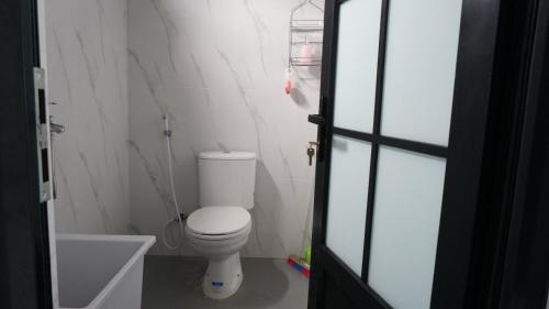 a white bathroom with a toilet and a bath tub at The Kaluna Resort in Lamno