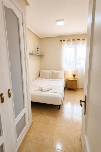a white bed in a room with a window at Raffaelas vacation apartment in Torrevieja