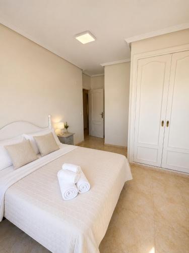 a bedroom with a large white bed with towels on it at Raffaelas vacation apartment in Torrevieja