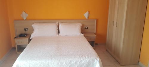 a bedroom with a white bed with two night stands at Hotel Trasimeno Bittarelli in Castiglione del Lago