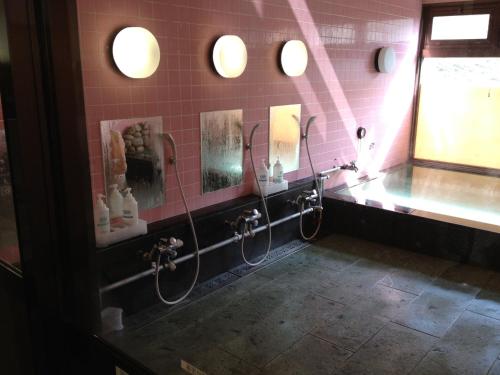 a bathroom with two showers and a sink and mirrors at Iyashinoyado Rodem in Morioka