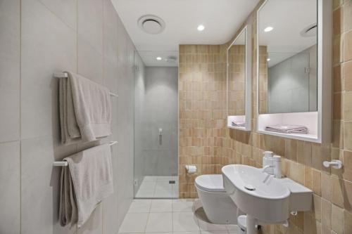 a bathroom with a sink and a toilet and a mirror at Modern Beach Ocean View 1 BDR Parking Balcony AC in Sydney