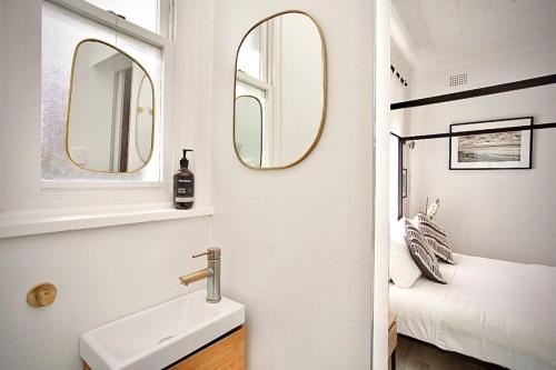 a bathroom with a sink and two mirrors at Bondi Surf Cottage in Sydney