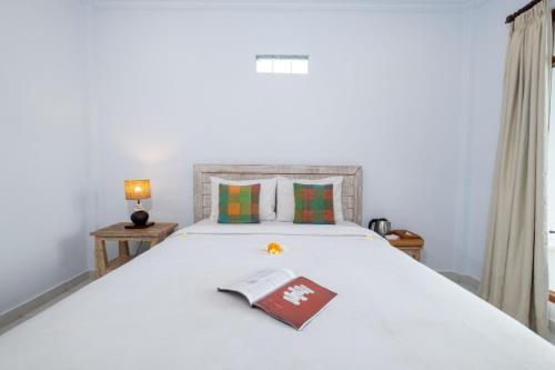 a bedroom with a white bed with a book on it at Ayu Shanti Guest House Ubud in Ubud