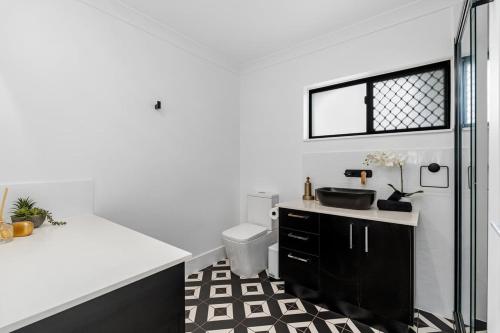 a white bathroom with a sink and a toilet at Absolute Beachfront Retreat - Private Beach TOOGOOM in Fraser Island