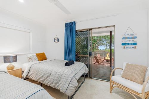 a bedroom with two beds and a chair and a balcony at Absolute Beachfront Retreat - Private Beach TOOGOOM in Fraser Island