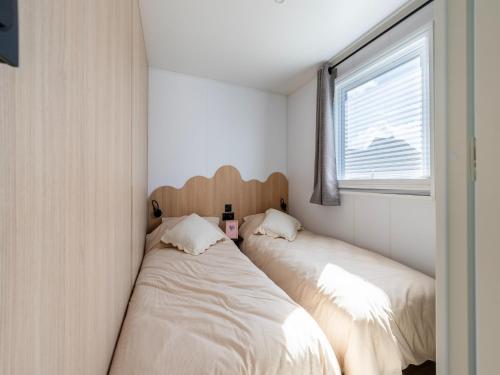 two beds in a small room with a window at Caravan Bredene by the sea in Bredene