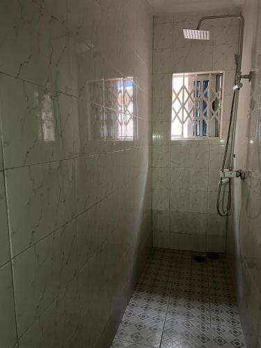 a bathroom with a shower and a tiled floor and a shower at Mavis Lodge in Janman