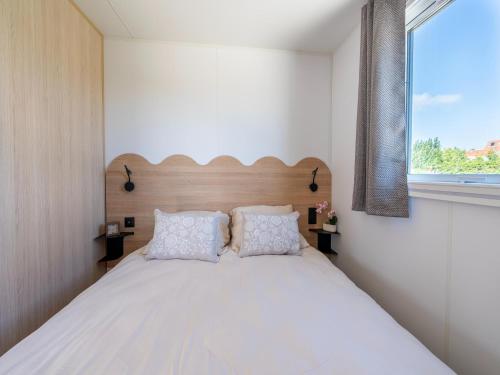 a bedroom with a large white bed with a window at Caravan Bredene on the coast in Bredene