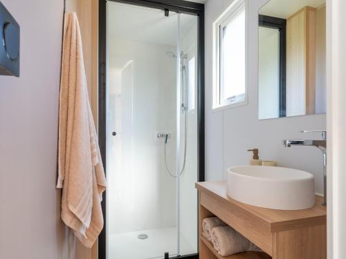 a white bathroom with a sink and a shower at Caravan Bredene on the coast in Bredene