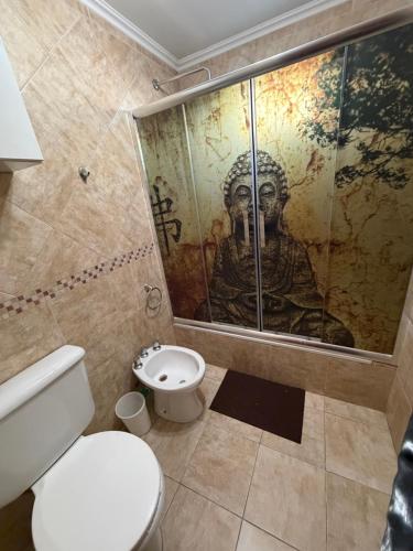 a bathroom with a toilet and a shower with a mural at Refugio serrano in Tandil