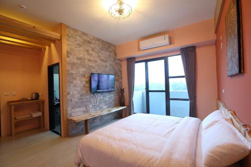 花蓮市にあるHualien Shiado B&Bのレンガの壁にテレビとベッドが備わるベッドルーム1室が備わります。