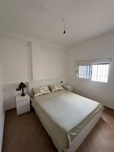 a white bedroom with a bed and a window at La Vista Azul in Belyounech 