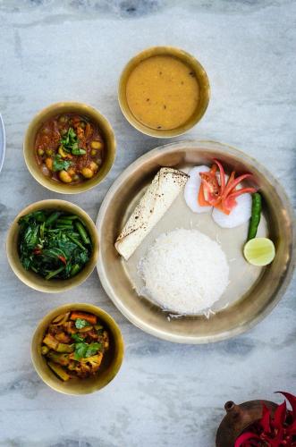 a table with plates of food with rice and vegetables at ROKPA Guest House in Kathmandu