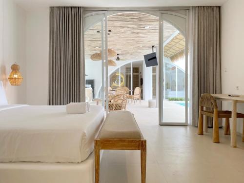 a bedroom with a white bed and a dining room at Villa Sei Uluwatu by LODGELINK BALI in Uluwatu