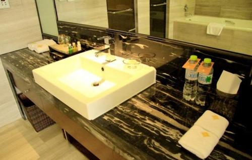 a bathroom with a white sink and a black counter at Huai'an Jinling Hotel in Huai'an