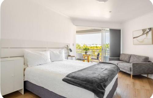 a bedroom with a large bed and a living room at Top Floor , Ocean and Resort Pool Views at Alex Beach Resort for 2 !!! in Alexandra Headland