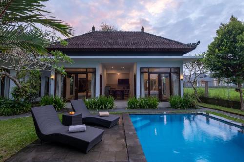 a villa with a swimming pool in front of a house at Ayu Shanti Guest House Ubud in Ubud