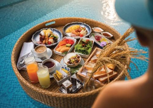 a basket of food with breakfast foods and orange juice at Kalanan Riverside Resort in Nonthaburi