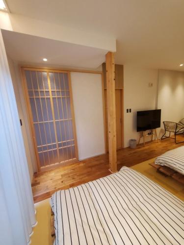 a bedroom with a bed and a flat screen tv at tomariel in Ō-shima