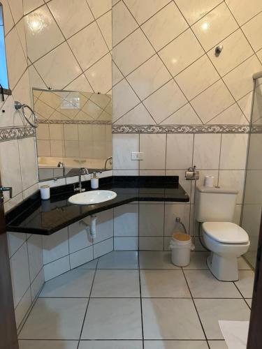 a white bathroom with a toilet and a sink at Casa aconchego Casa ampla e completa no centro in Naviraí