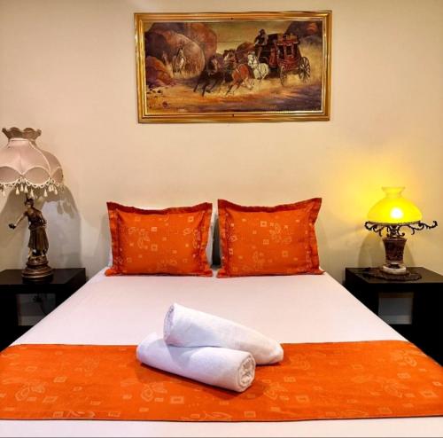 a bedroom with two beds with orange pillows and a painting at Hotel Plaza Garibaldi in Caldas