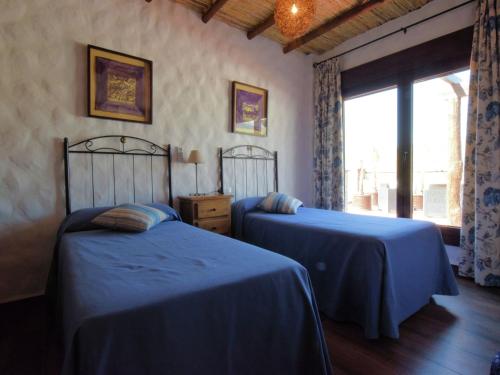 a bedroom with two beds with blue sheets and a window at Beautiful villa with jacuzzi in Canillas de Albaida