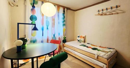 a bedroom with a bed and a table and a table and chairs at 낙원파크포도홈 in P'ungnyŏn-gol