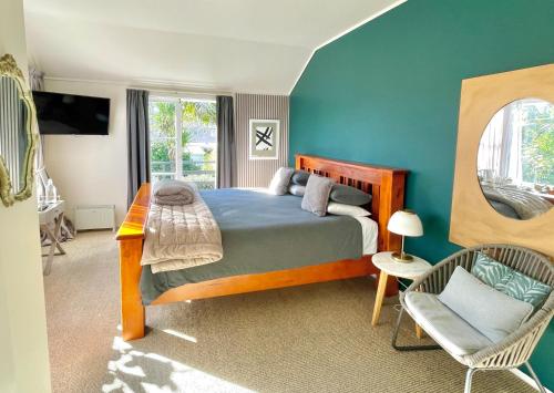 a bedroom with a bed and a chair and a mirror at Bavaria Boutique Hotel in Auckland
