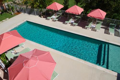 a swimming pool with pink umbrellas and chairs next to it at The Roy in Rainbow Beach