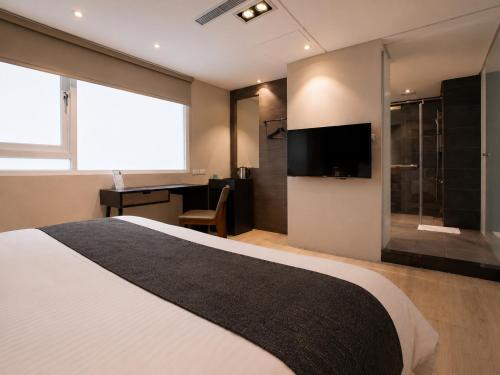 a bedroom with a large bed and a television at P&F Hotel in Taichung