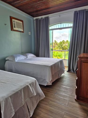 a bedroom with two beds and a large window at Casa em Salinas in Salinópolis