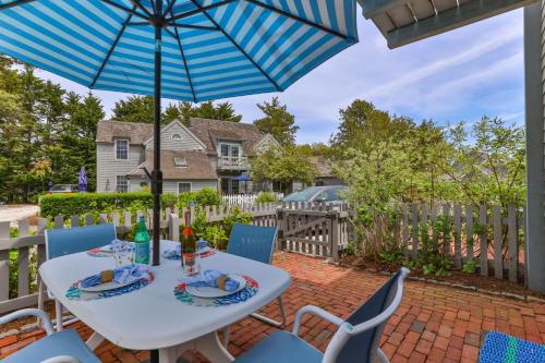 a patio with a white table and chairs and an umbrella at Hydrangea Lane Beach Cottage in Mashpee