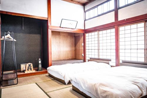 a bedroom with two beds in a room with windows at 白灯-Hakuto- Muikamachi in Minami Uonuma