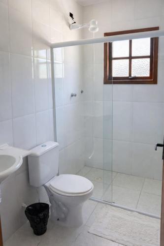 a white bathroom with a toilet and a sink at Pousada dos Pescadores in Bertioga