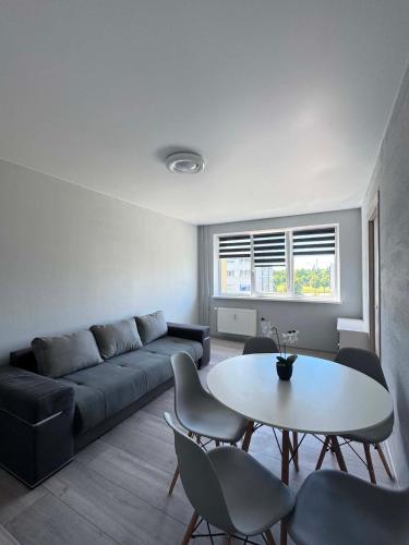 a living room with a couch and a table and chairs at 3 kambarai in Naujoji Akmenė