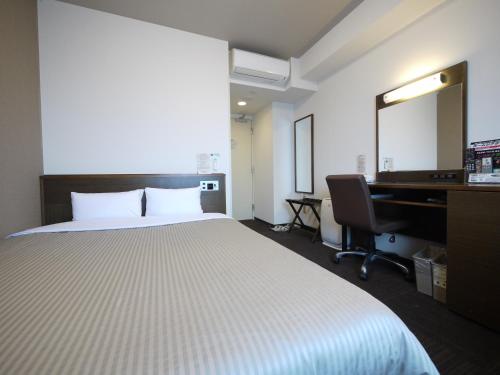 a bedroom with a bed and a desk and a computer at Hotel Route-Inn Ishinomaki Kanan Inter in Ishinomaki