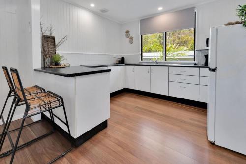 a kitchen with white cabinets and a refrigerator at Birdwing Retreat in Picnic Bay