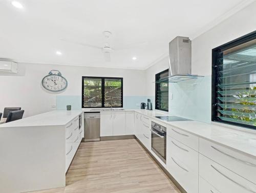 a kitchen with white cabinets and a clock on the wall at Alma Rocks in Arcadia