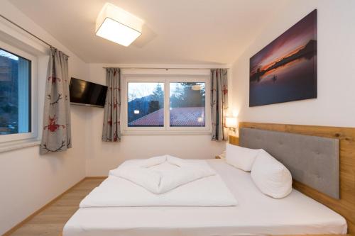 ein weißes Bett in einem Zimmer mit Fenster in der Unterkunft Ferienhaus Alpenherz in Finkenberg