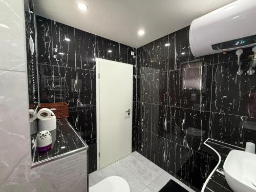 a black tiled bathroom with a toilet and a sink at Altstadtnest mit großem Garten in Bad Sooden-Allendorf