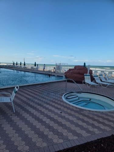 a swimming pool next to a beach with two chairs at The Surf Shack at Harbour Beach Resort in Daytona Beach