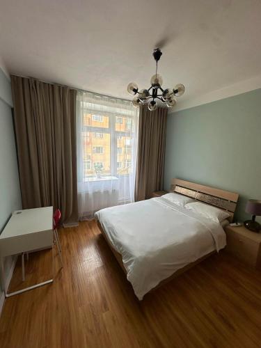 a bedroom with a white bed and a chandelier at Russian Embassy Apartment in Ulaanbaatar